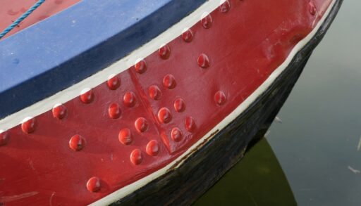Painted rivets on a red, blue and black aluminum boat.