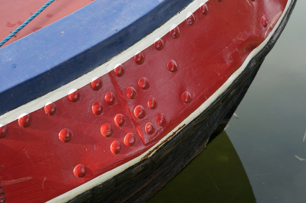 Painted rivets on a red, blue and black aluminum boat.