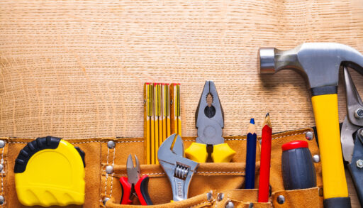 Tools sticking out of a toolbelt, including a tape measure, pliers and hammer.