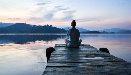 Young woman sitting on a dock at sunset.