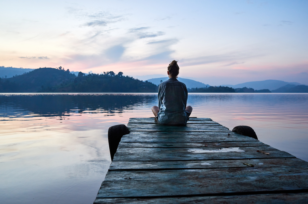 Young woman sitting on a dock at sunset.