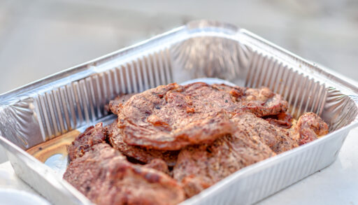 Grilled steaks in a silver aluminum pan.