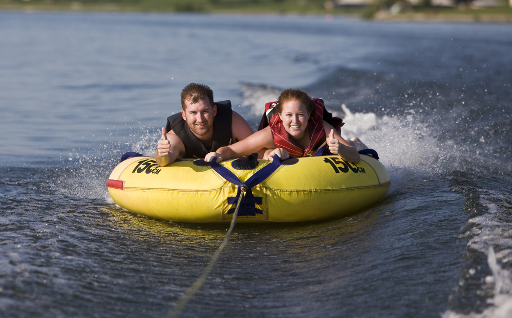 Young man and woman riding a yellow water tube.