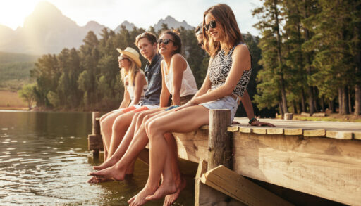 Group of young friends sitting on a dock together.