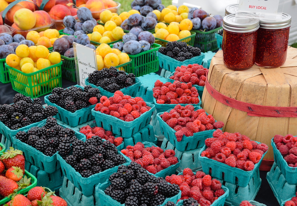 Raspberries and blackberries stacked in blue cartons.