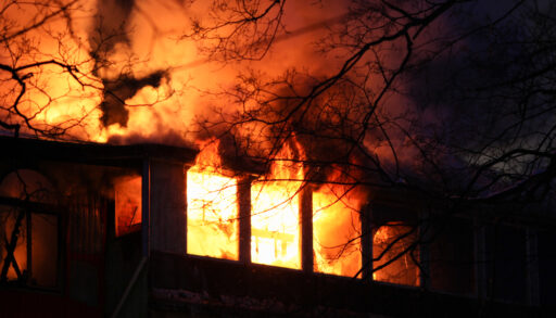 Residential house on fire with flames coming through windows.