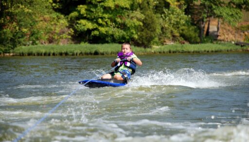 Boy kneeboarding on a lake.