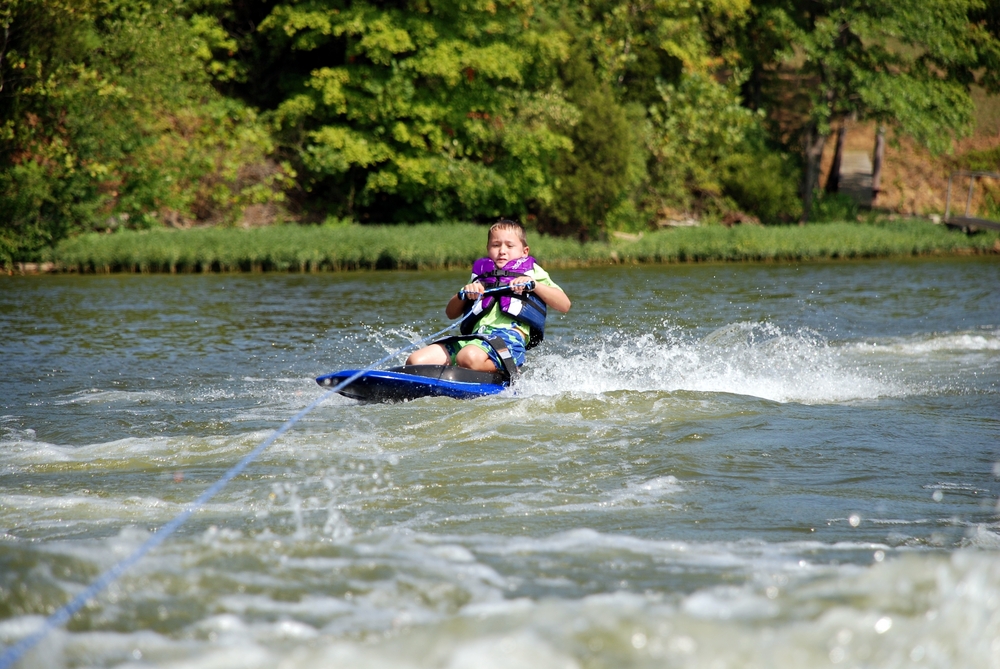 Boy kneeboarding on a lake.