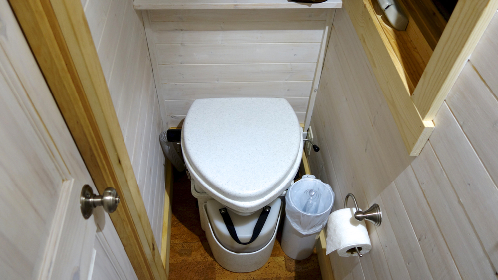 White composting toilet in a small bathroom.