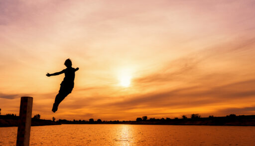 Person jumping off a dock at sunset.