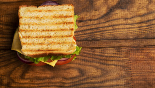 Sandwich on top of a dark, wooden cutting board.