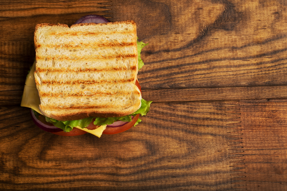 Sandwich on top of a dark, wooden cutting board.