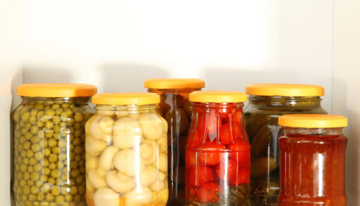 Glass jars filled with different canned vegetables.