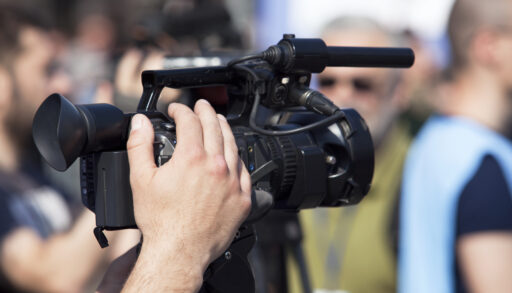 Close-up of a person holding a black video camera.