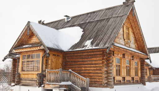 Wooden log cabin covered in snow.