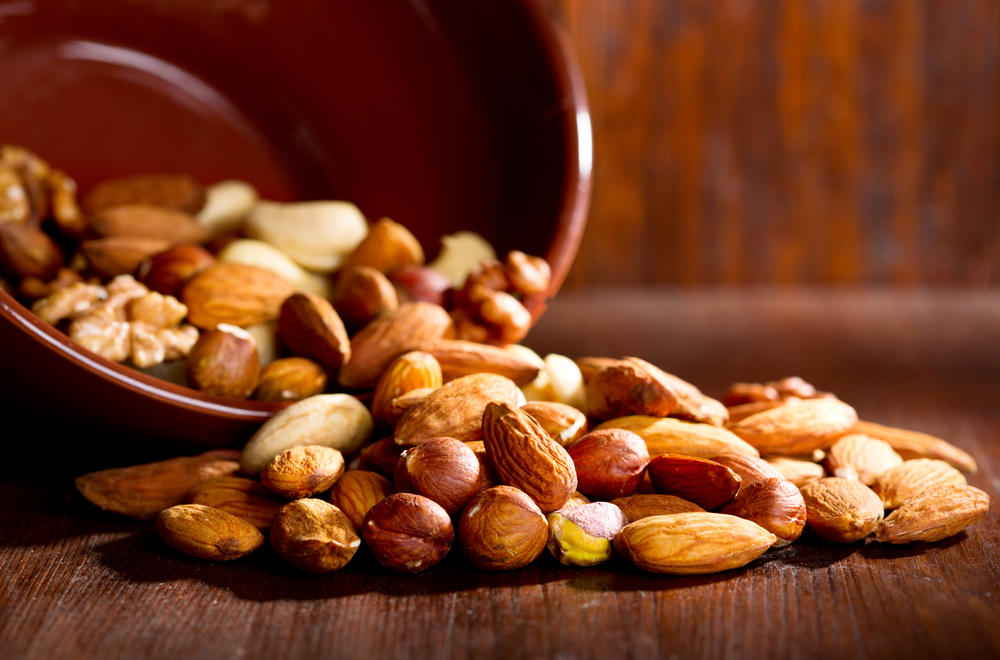 Mixed nuts poured onto a wooden table.
