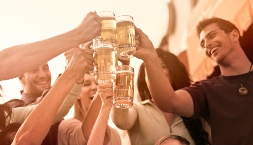 Group of people smiling and raising beer glasses.