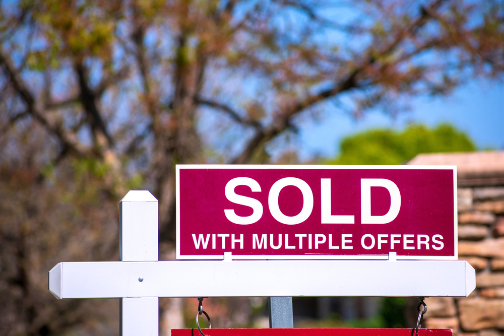 Red real estate sign reading "Sold with multiple offers."