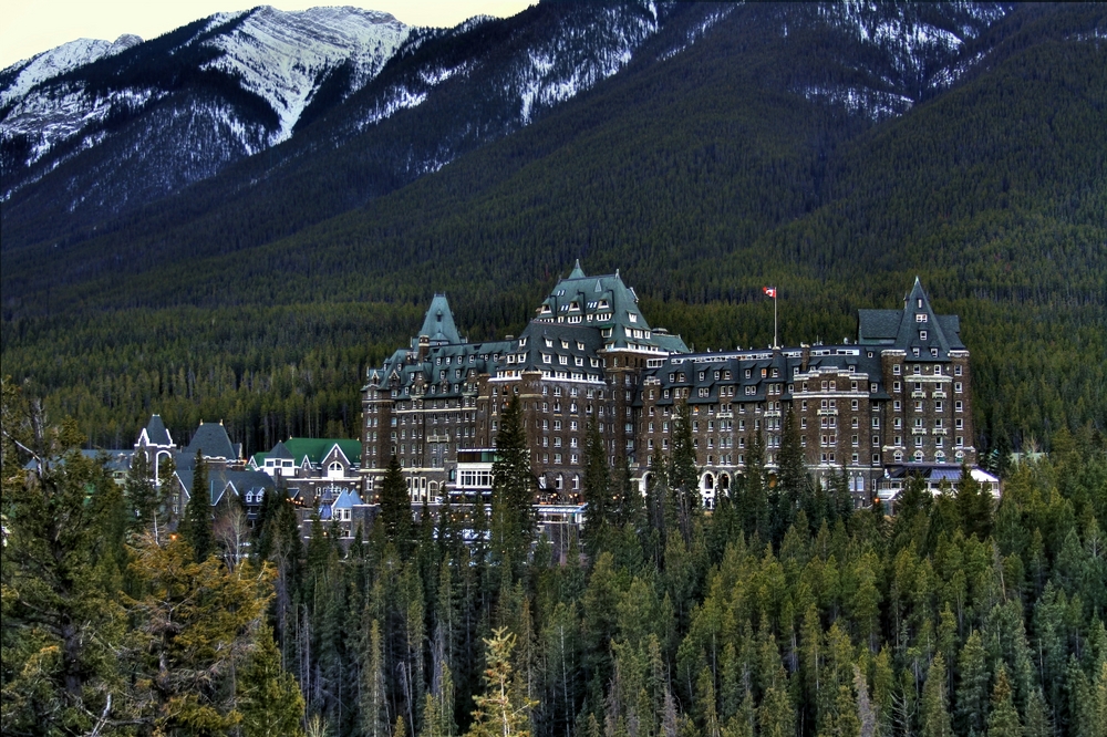 Banff Springs Hotel next to a mountain surrounded by trees.