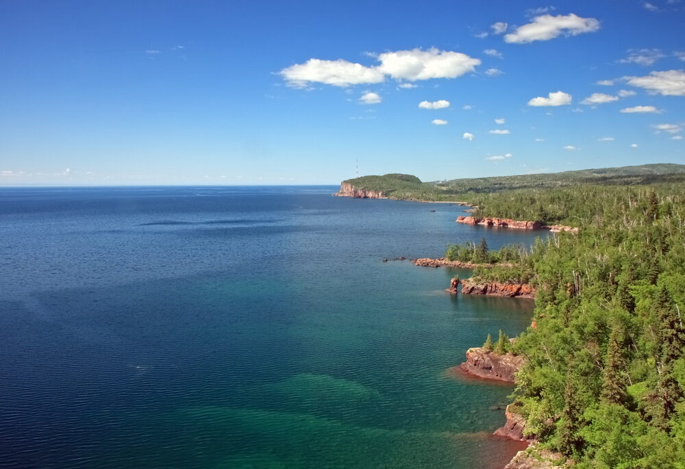 Aerial view of the blue waters and green trees of Lake Superior.