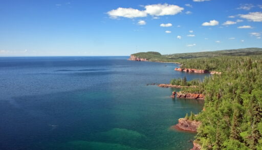 Aerial view of the blue waters and green trees of Lake Superior.