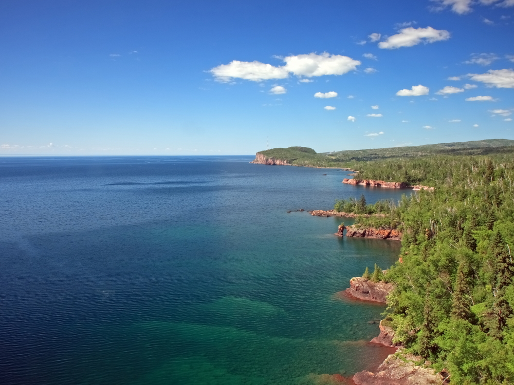 Aerial view of the blue waters and green trees of Lake Superior.