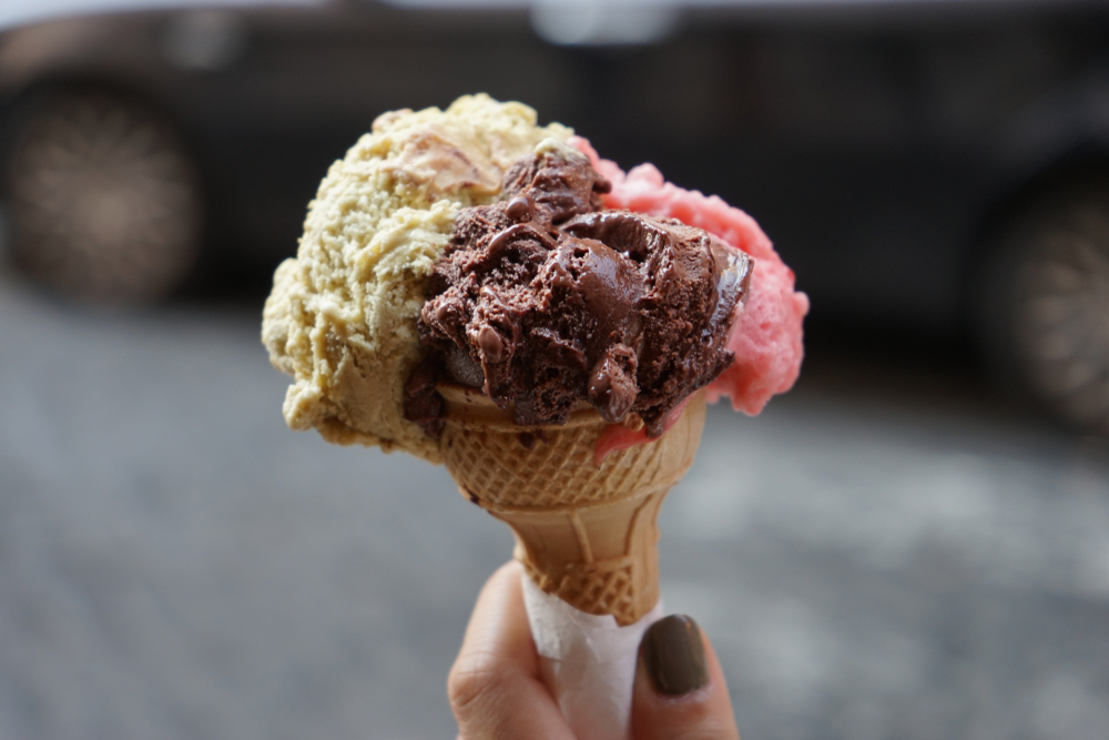Woman holding an ice cream cone with vanilla, chocolate and strawberry ice cream.