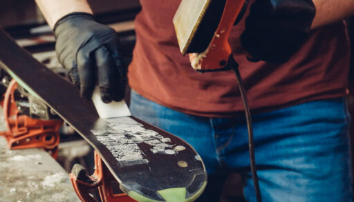 Close-up of a person applying wax to the bottom of a ski.