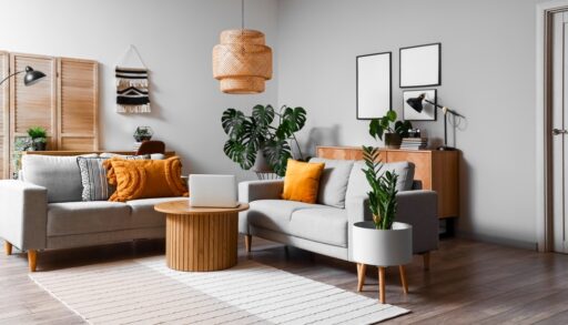 Interior of a living room with grey walls and couches, with yellow pillows and green plants.