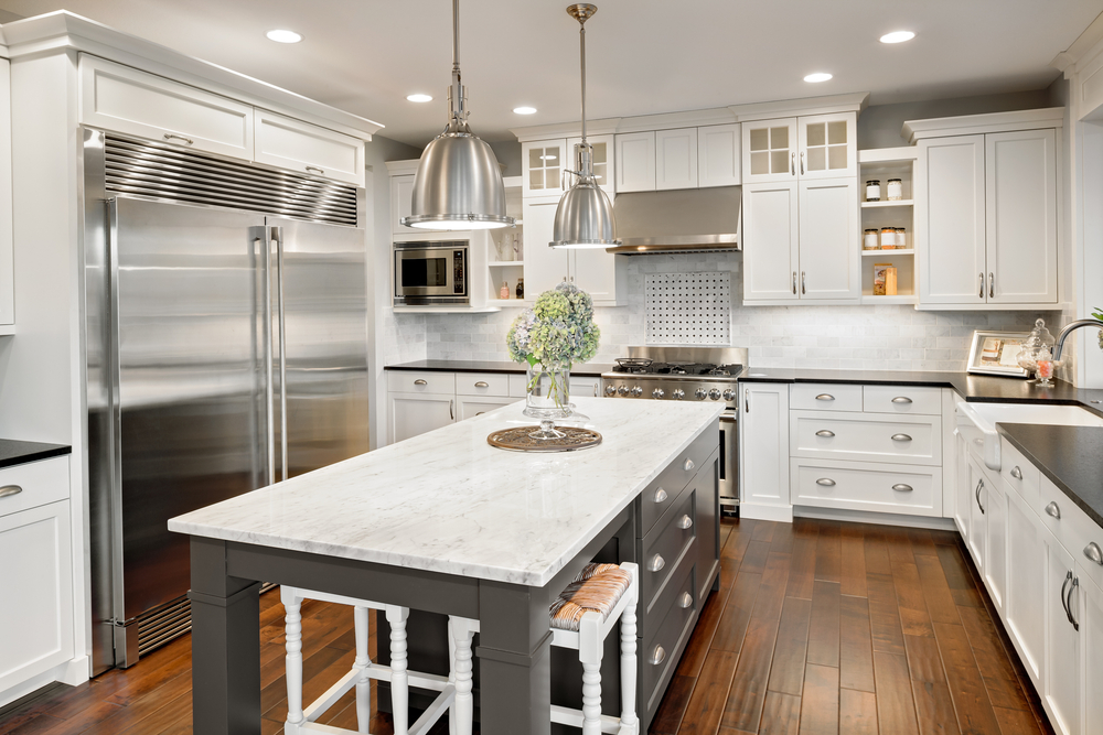 Interior of a modern kitchen with a large silver fridge and grey island.