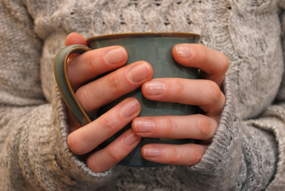Close-up of a woman's hands holding a blue-grey coloured mug.