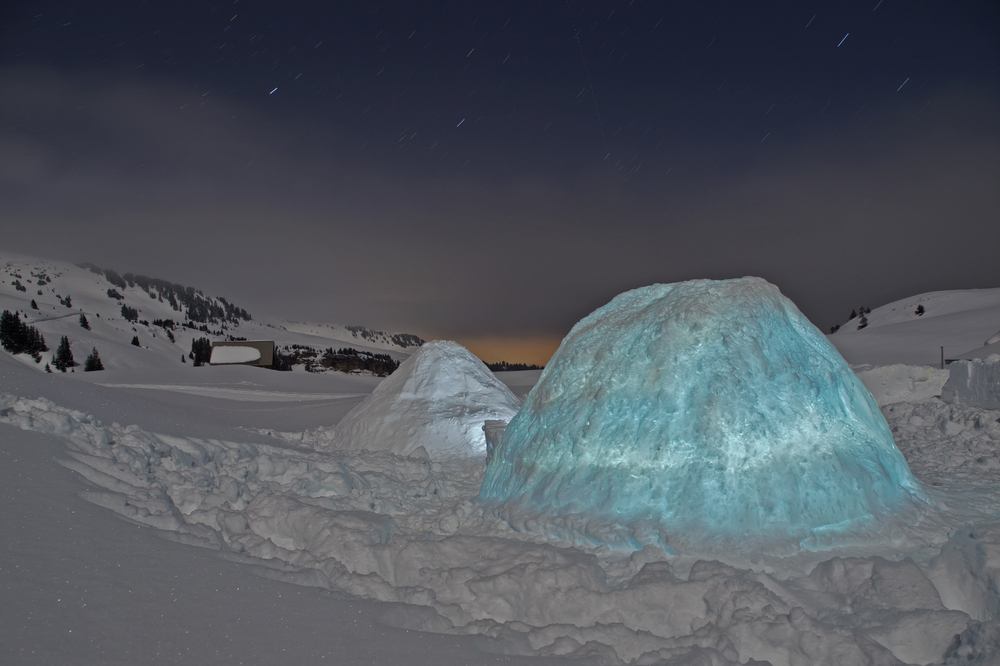 Illuminated igloo at night.