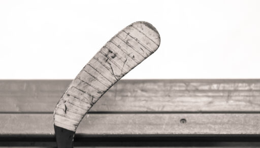 Hockey stick blade leaning against the top of hockey boards.
