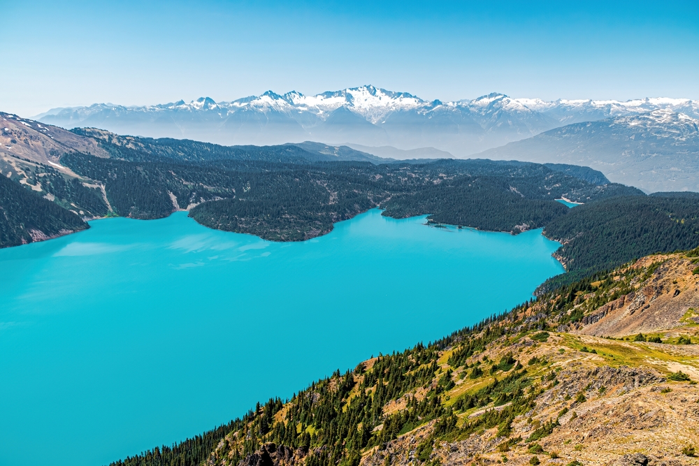 Turquoise waters of Garibaldi Lake surrounded by snow-covered mountains in British Columbia, Canada.