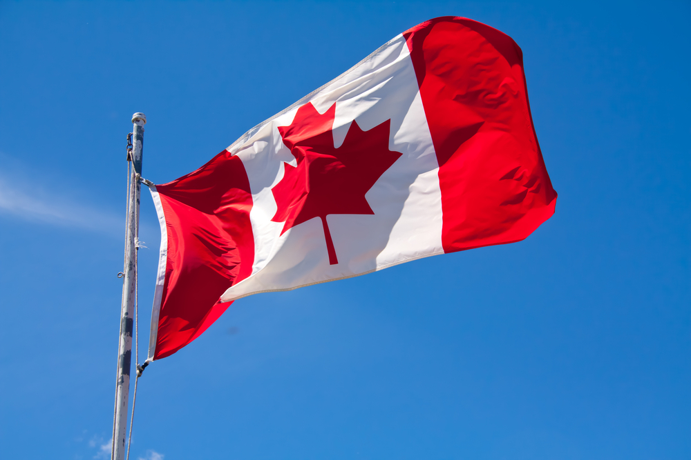 Canadian flag against a blue sky waving in the wind.