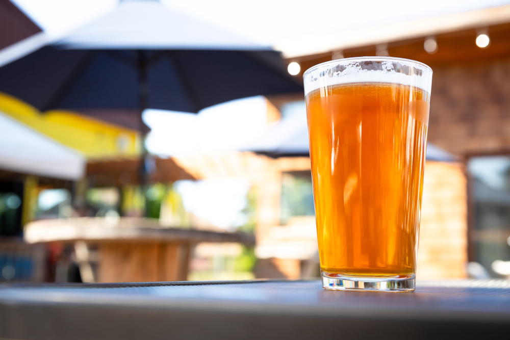 Glass of light-coloured beer on a patio table.