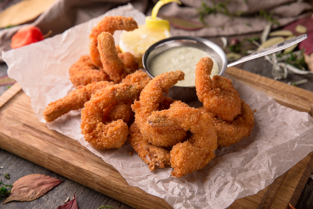 Close-up of deep-fried shrimp next to a dipping sauce.