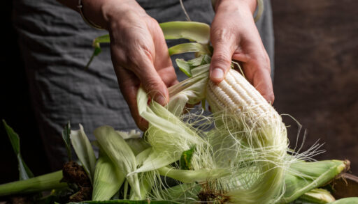 Close-up of a woman shucking corn.