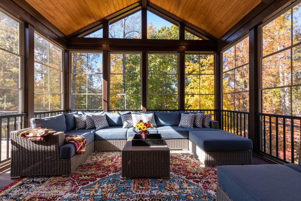 Screened in porch with large windows, a vaulted roof, and a large sectional.