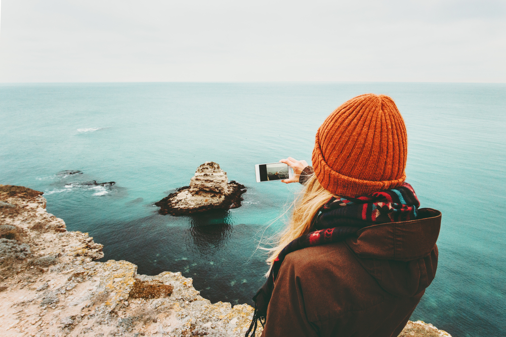 Woman in an orange hat taking a photo with her smartphone.