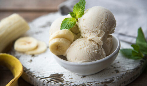 Bowl of banana ice cream with banana slices and mint.