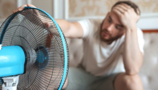 Young man using a fan to cool off.