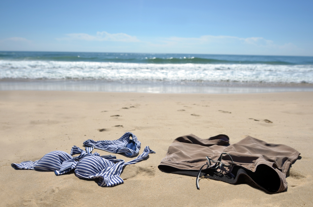 A man and woman's bathing suits on a beach.