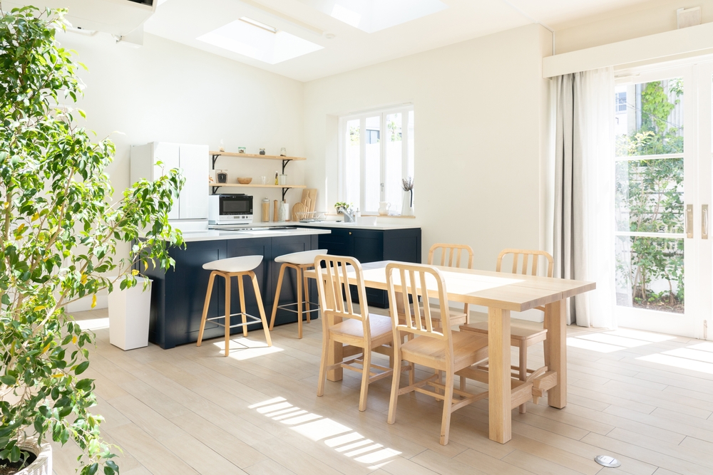 Kitchen interior with bright walls, blue cabinets and a wooden dining table.