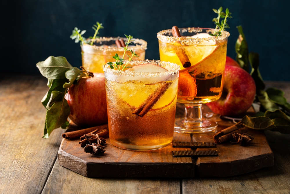 Three glasses of a cider margarita garnished with cinnamon sticks.