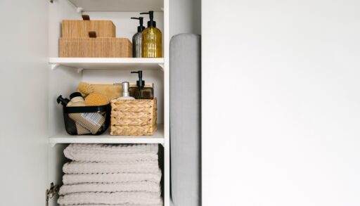 Close-up of a bathroom cabinet with folded towels and soap bottles.