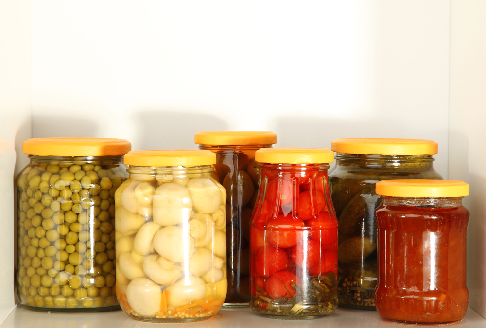 Different vegetables pickled in jars on a shelf.