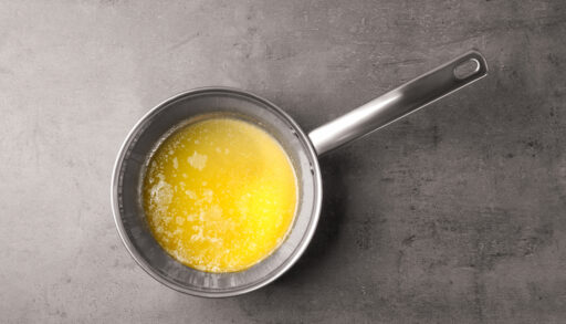 Overhead of a silver saucepan with melted butter.