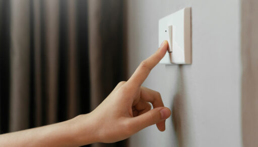 Close-up of a woman's hand pressing a light switch.