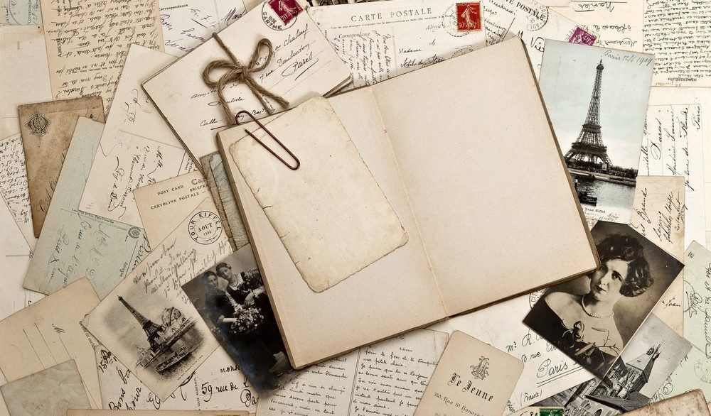 Empty scrapbook with old photos and letters laying around it.